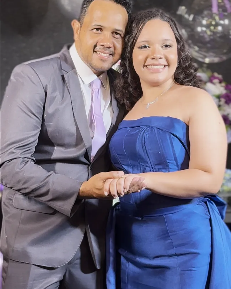 Debutante de vestido azul posando de mãos dadas com o pai durante a festa de 15 anos